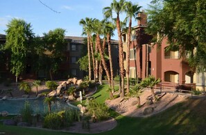 A resort with a swimming pool, palm trees, and a landscaped garden.