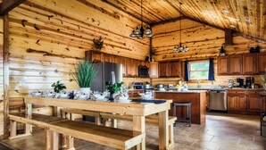 Eine holzgetäfelte Küchenzeile mit Holztisch und Bänken, inklusive Kühlschrank, Mikrowelle und Geschirrspüler.