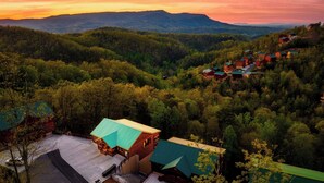 Eine Lodge mit einem grünen Dach, umgeben von bewaldeten Hügeln.