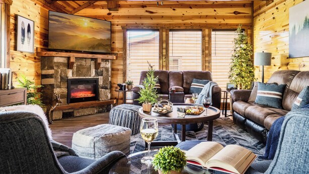 Ein gemütliches Blockhaus-Interieur mit Kamin, Ledersofas, einem Couchtisch und einem Weihnachtsbaum.