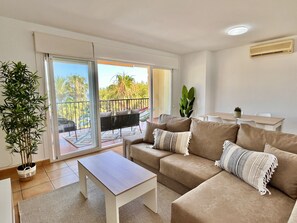 A modern living room with a sofa, coffee table, and a balcony with a view.