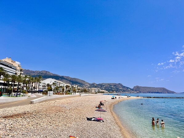 Une plage de galets, quelques parasols et des gens.