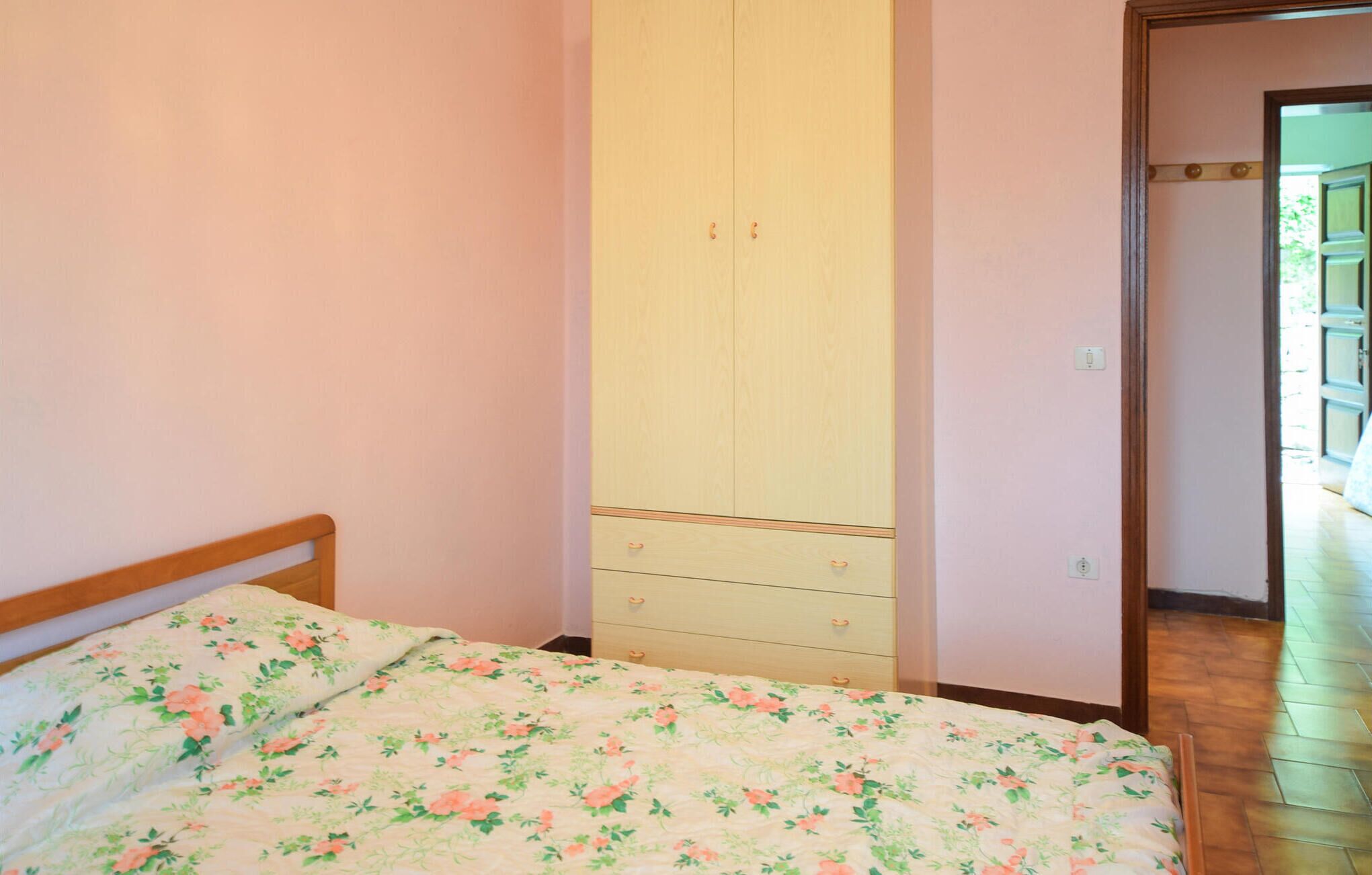 A bedroom with a bed, a wardrobe, and a door leading to another room.