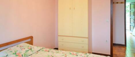 A bedroom with a bed, a wardrobe, and a door leading to another room.