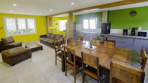 A bright kitchen with a microwave, stove, and coffee maker. There is a dining area with a wooden table and chairs. - Le Gîte des Remparts (CHAOURCE)