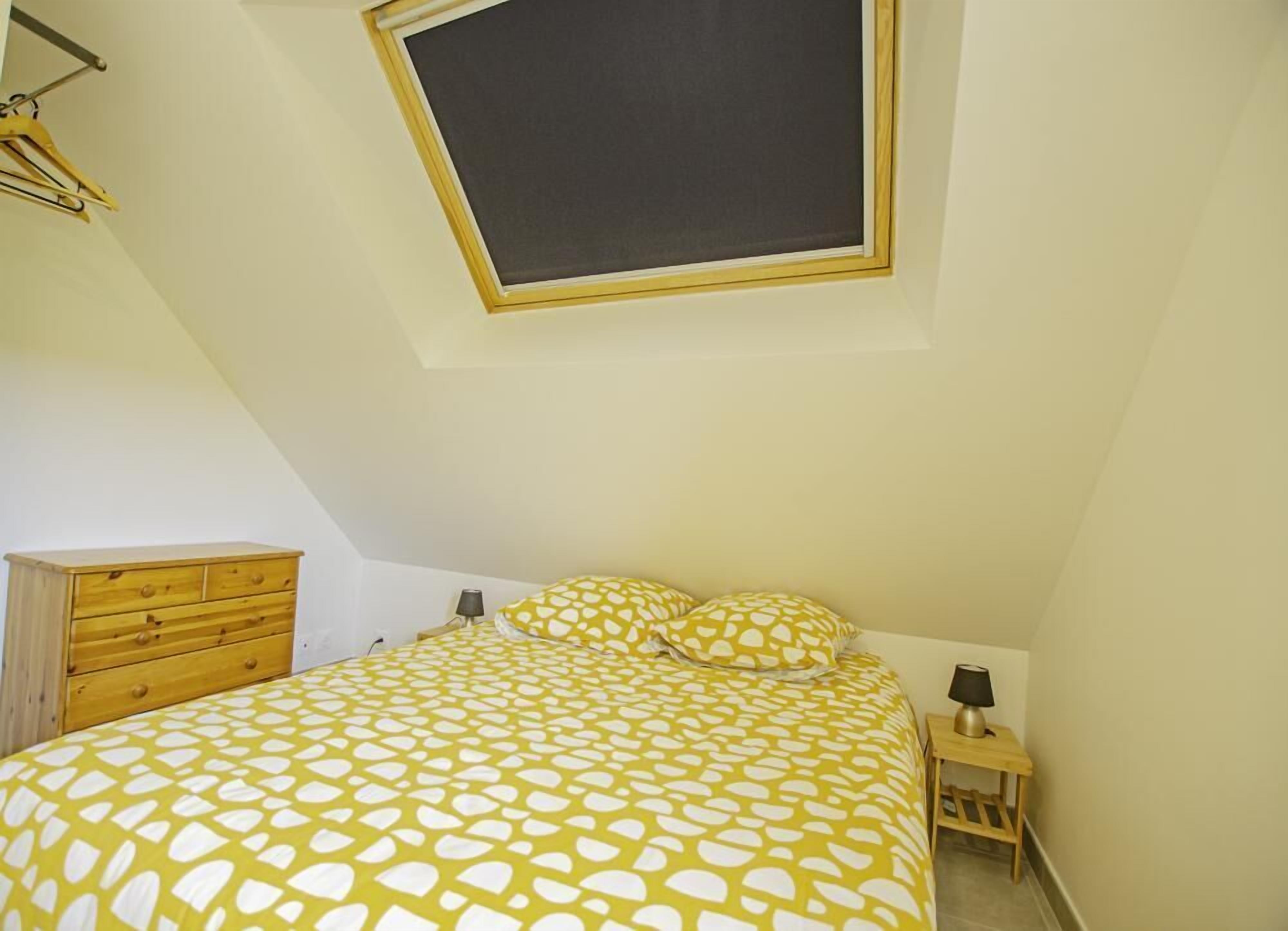 A bedroom with a bed, a nightstand, a dresser, and a window with a blackboard.