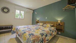 A bedroom with a bed, a wall-mounted mirror, a window, and a wall-mounted light fixture. - Le Gîte des Remparts (CHAOURCE)