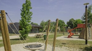 A playground with swings, a picnic table, and a climbing structure. - Le Gîte des Remparts (CHAOURCE)