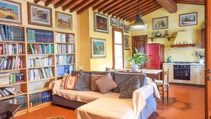 A cozy living room with a sofa, a bookshelf, and a dining area with a table and chairs. - Gorgeous home in Santa Maria a Monte (Santa Maria a Monte)