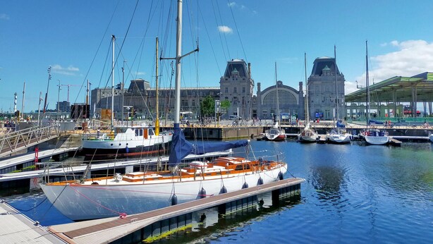 A marina with boats docked, a large building with a distinctive roof, and a covered walkway. - Cozy apartment in Oostende with WiFi (Oostende)