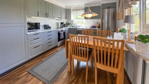 Una cocina moderna con armarios grises, una mesa de comedor de madera y un amplio ventanal que proporciona luz natural.