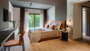 Quarto moderno com cama grande, piso de madeira e vista para o verde lá fora.