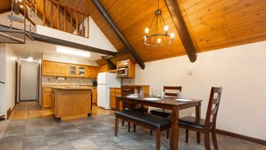 A spacious kitchen with wooden cabinets, a dining table with chairs, and a stone-tiled floor. - Cozy Hyalite Cabin! Minutes from MSU, Downtown Bozeman & Hyalite Canyon! (Bozeman)