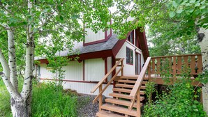 A wooden staircase leading to a white building with a dark roof, surrounded by greenery. - Cozy Hyalite Cabin! Minutes from MSU, Downtown Bozeman & Hyalite Canyon! (Bozeman)