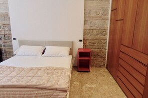 Une chambre à coucher avec un lit, une table de chevet rouge et une armoire en bois.