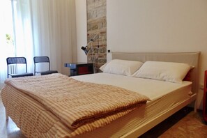 Una camera da letto con un letto, un comodino, una lampada e due sedie.