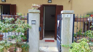 Een gevel met een poort, plantenbakken en een deur met een bord.
