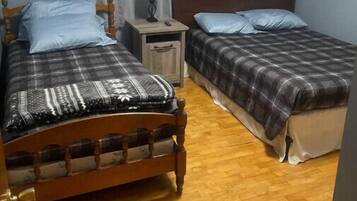 A room with two wooden beds, a nightstand with a lamp, and a window with curtains.