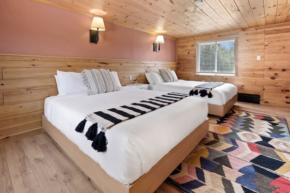 Cozy bedroom with two single beds, throw blankets, and a colorful rug.