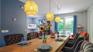 A dining area with a wooden table set for six, surrounded by upholstered chairs. - 4 bedroom cozy home in Zonnemaire (Zonnemaire)