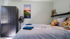 A bedroom with a bed, a wardrobe, a wall-mounted fan, a framed picture, and a shelf with a lamp. - 4 bedroom cozy home in Zonnemaire (Zonnemaire)