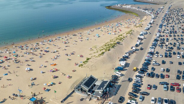 An aerial view of a beach with numerous umbrellas and people. There is a parking lot adjacent to the beach with many cars. - 4 bedroom cozy home in Zonnemaire (Zonnemaire)