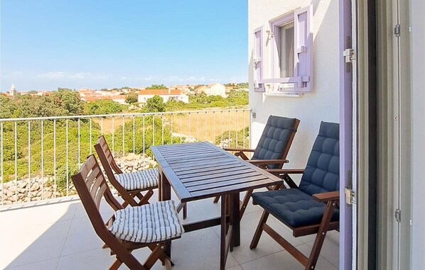 A balcony with a table and chairs, a view of the surrounding area, and a building with a window.