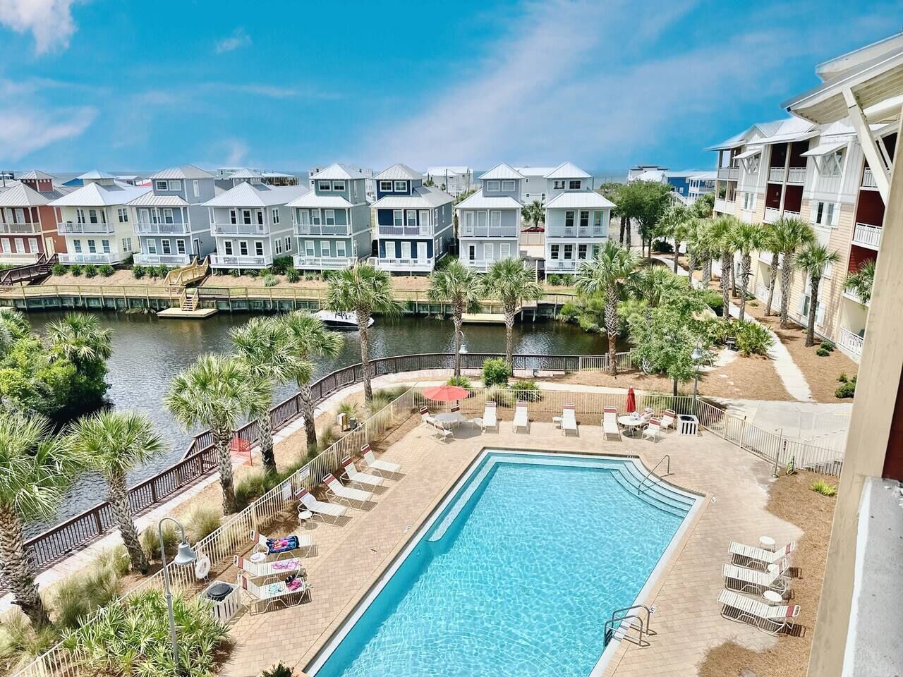 A hotel with a swimming pool, palm trees, and a waterfront view.