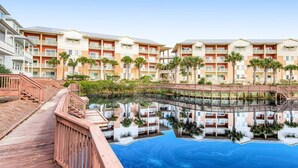 Ein Resort mit mehrstöckigen Gebäuden, einem Schwimmbecken und einem Holzsteg.