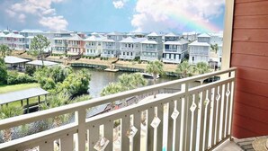 Ein Balkon mit Blick auf einen Fluss, Häuser und einen Regenbogen.