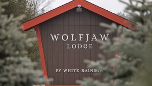 Ein Gebäude mit der Aufschrift "WOLFJAW LODGE" und "BY WHITE RAINBOW" an der Fassade.