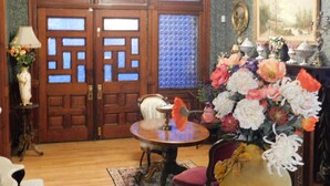 A room with wooden double doors, a round table, and floral arrangements. - Johnstone Mansion (Keokuk)