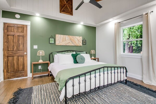 A bedroom with a bed, nightstands, a green wall, a window with curtains, and a ceiling fan. - HOT TUB, Lake Front, King Bed (Wilson)