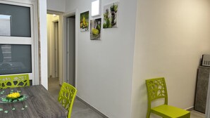 Een eetgedeelte met een houten tafel, groene stoelen en een klein decoratief plantje aan de muur.