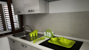 Een moderne keuken met een roestvrijstalen spoelbak, een zwart fornuis en groene keukenaccessoires.