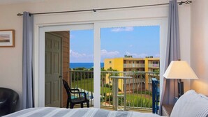 Habitación de hotel con cama, una silla, una mesa y vistas a una piscina y edificios.
