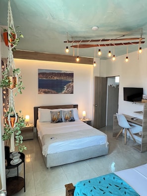 Une chambre à coucher moderne, comprenant un lit, des tables de chevet, un bureau, une chaise, un téléviseur et une œuvre d’art accrochée au mur.