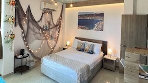 Une chambre à coucher comprenant un lit, des tables de chevet, un bureau, un luminaire suspendu et un climatiseur fixé au mur.