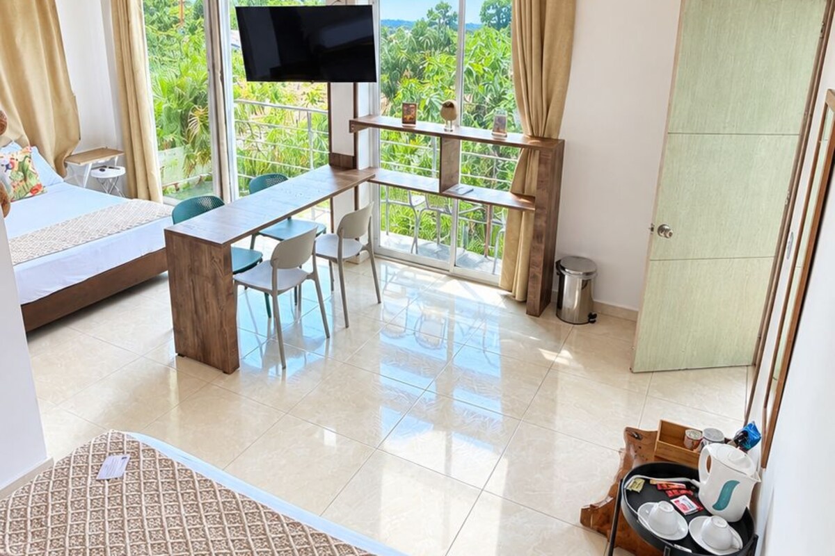 A bedroom with a bed, a desk, and a TV.