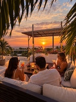 Vista al atardecer desde una terraza en la azotea con pérgola, zona de estar y plantas en macetas.