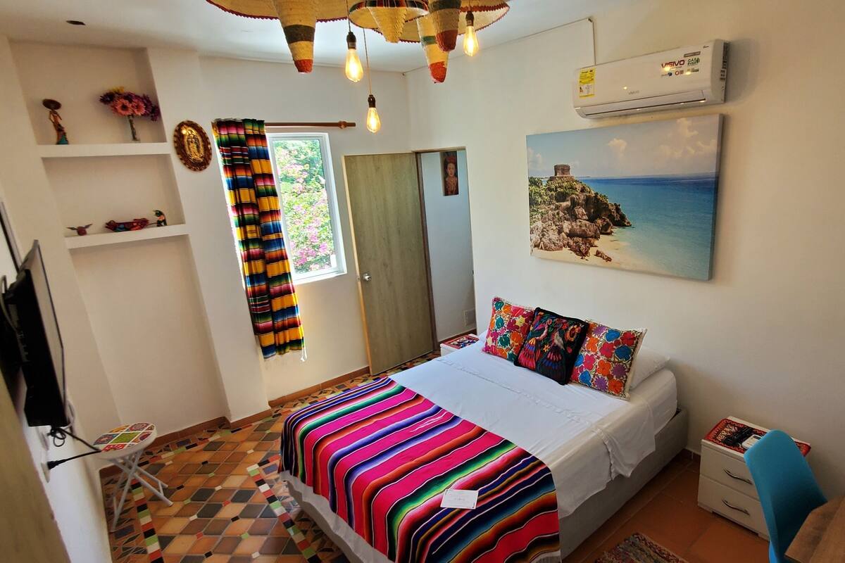 A bedroom with a bed, a TV, a desk, and a chair.