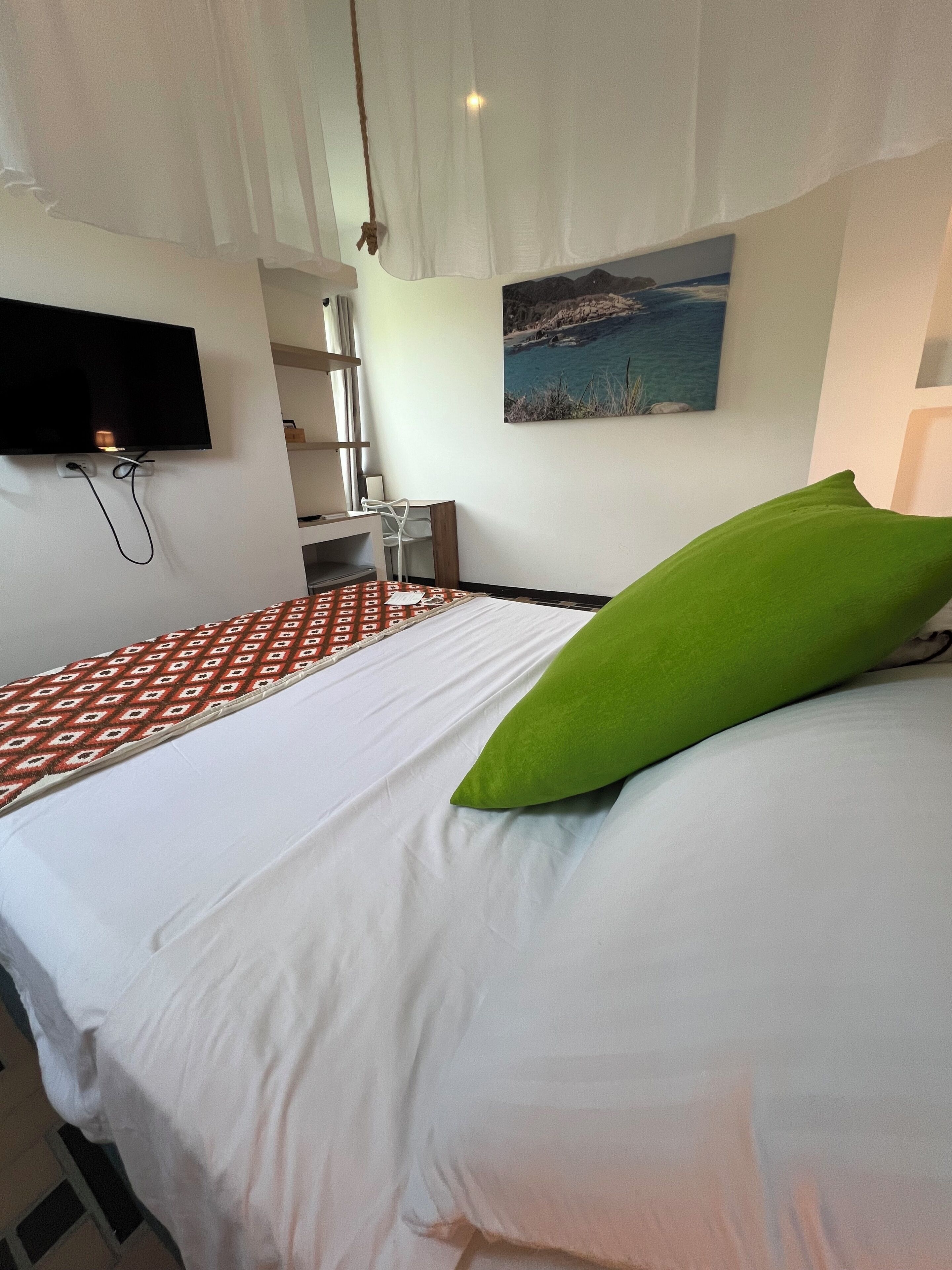 Ein Hotelzimmer mit Bett, Wandfernseher, Schreibtisch und Stuhl.