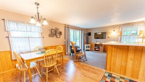 A cozy kitchen with wooden furniture, a dining table, and a colorful rug. - Lone Pine: S'mores, Sunshine, and Stanley Lake Days (Iron River)