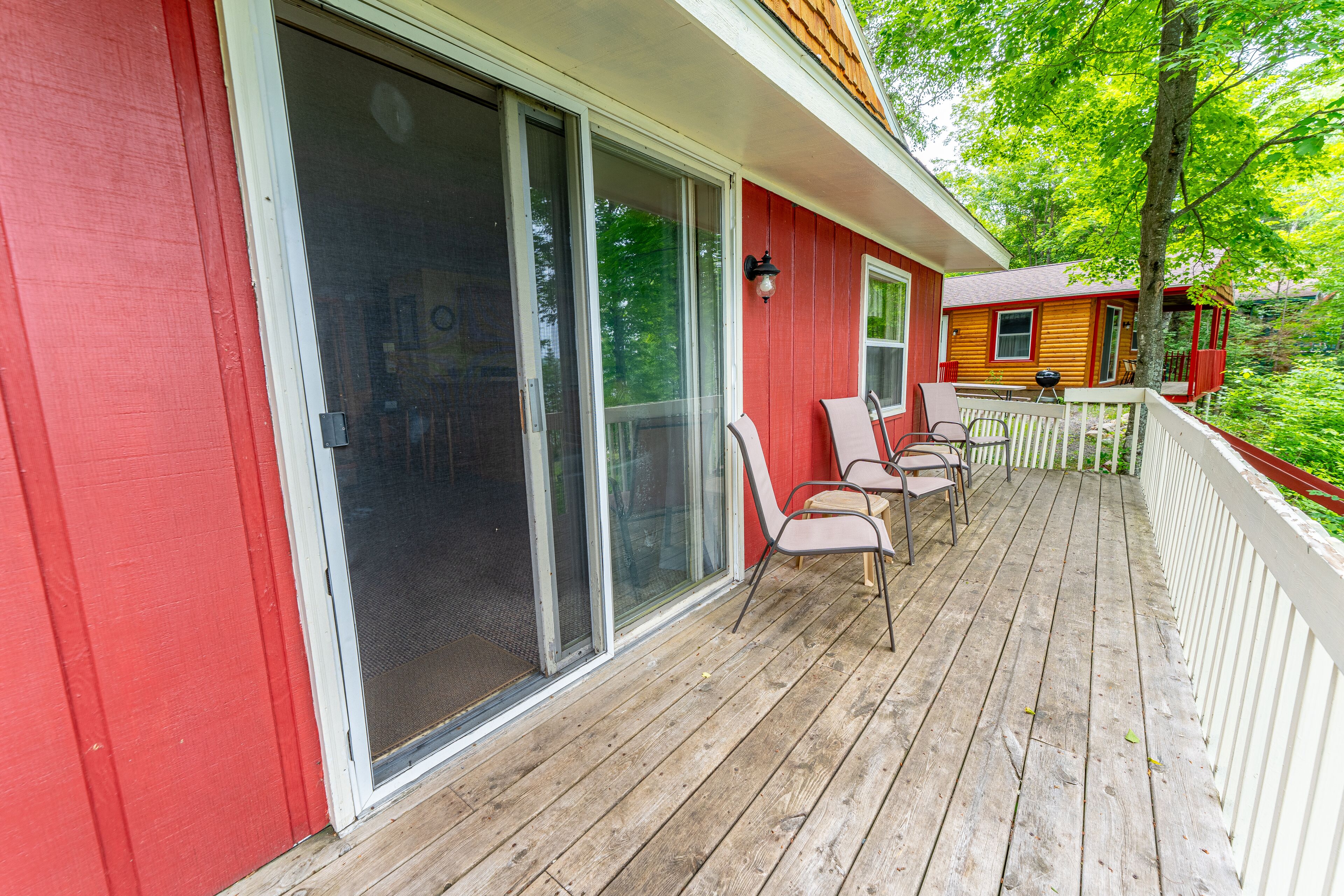 Un bâtiment rouge doté d’une terrasse en bois, de portes coulissantes en verre et d’un espace salon extérieur.