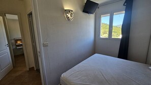 A bedroom with a bed, a wall-mounted TV, a window with a view, and a door leading to another room. - Appartement SARAH Vue mer- Clim- Wi-fi (FAVONE CONCA)
