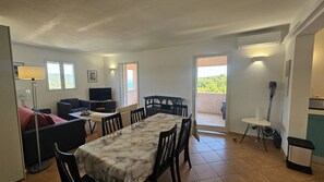 A dining area with a marble table, chairs, a sofa, a TV, and a balcony with a view. - Appartement SARAH Vue mer- Clim- Wi-fi (FAVONE CONCA)