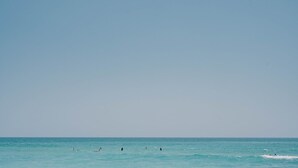 A clear view of the ocean with several people swimming and surfing. - Newly remodeled condo on Wrightsville Beach steps away from the ocean!  (Wrightsville Beach)