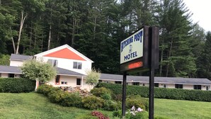 A motel sign with a 'VACANCY' notice, surrounded by well-maintained landscaping and a building with a red roof. - Hitching Post Country Motel (Cornwall Bridge)