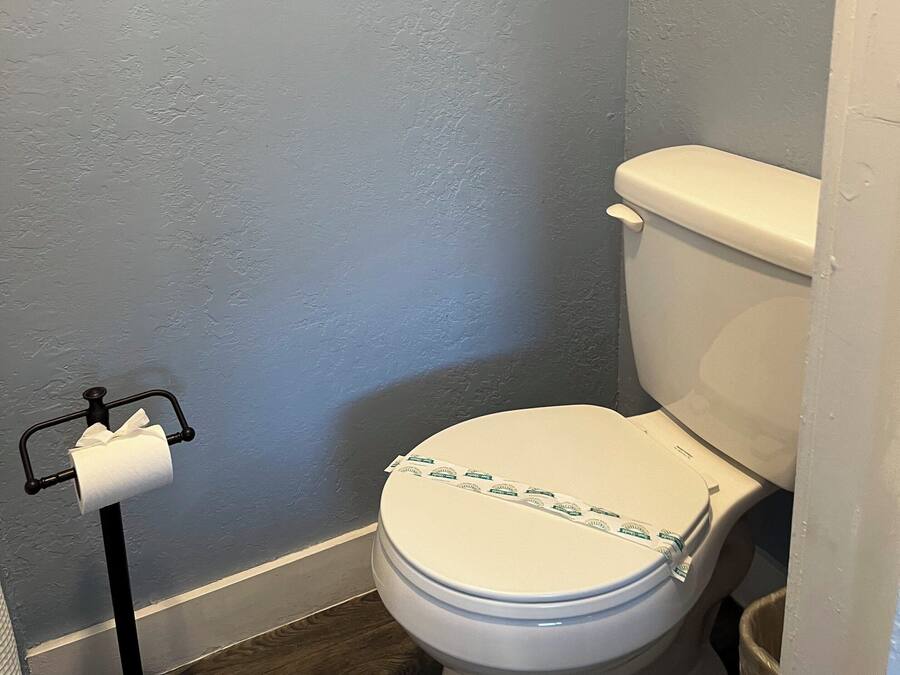 A bathroom with a toilet, a paper towel holder, and a blue textured wall.