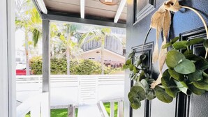 En modern hotellentrél med en glasdörr, en hängande växt och utsikt över gatan och grönområdena utanför.